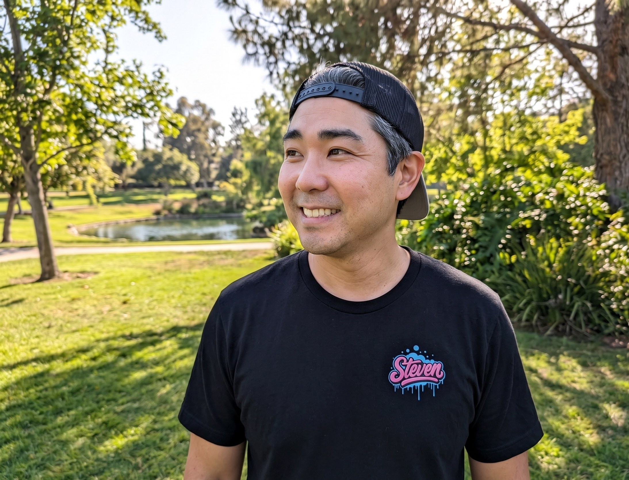 Man wearing a black t-shirt with a logo in a park